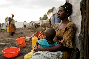 Eine Mutter mit ihrem Kind sitzt vor ihrem Zelt in einem Flüchtlingslager am Rande von Goma