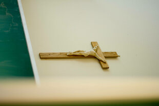 Ein Kruzifix an der Wand, das Bild ist um 90° nach rechts gedreht und erweckt den Eindruck dass das Kreuz liegt