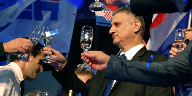 Der kroatische Politiker und viele andere Männer stoßen mit Sekt an