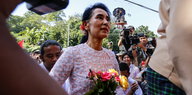 Eine Frau mit Blumen in einer Menschenmenge - es ist die Wahlsiegerin Aung San Suu Kyi