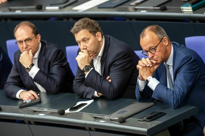 Friedrich Merz verfolgt die Debatte neben Lars Klingbeil und Alexander Dobrindt