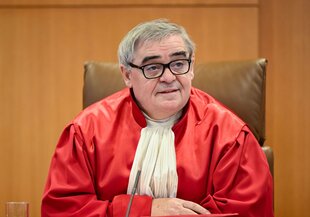 Peter Müller in der roten Robe eines Bundesverfassungsrichters, sitzend