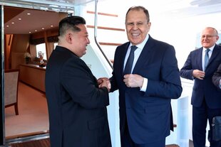 Kim Jong Un und Lawrow geben sich die Hand. Kim lächelt Lawrow an, Lawrow lächelt in die Kamera