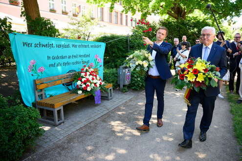 Bundespräsident Frank-Walter Steinmeier legt zusammen mit Nico Ruhle (SPD), Bürgermeister der Stadt Neuruppin, an der Gedenkstele für den von Rechtsextremisten getöteten Emil Wendland im Rosengarten Blumen nieder.