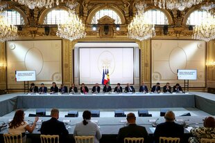 An einem großen Verhandlungstisc h sitzen viele Männer und wenige Frauen - in der Mitte Emmanuel Macron