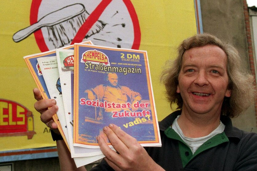 Redakteur Gerd Czerwinski hält 1998 Hempels-Ausgaben vor einem Werbeplakat hoch
