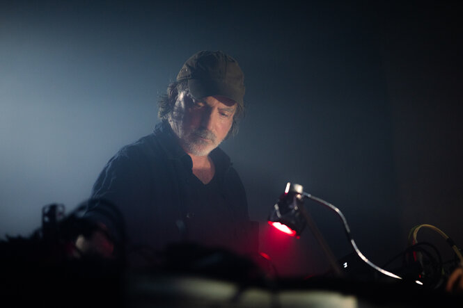 Mann im mittleren Alter mit Baseball-Cap steht vor einem Synthesizer
