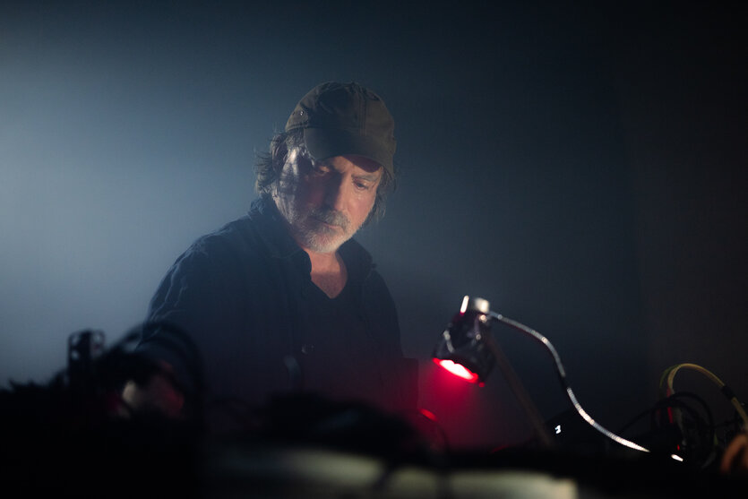 Mann im mittleren Alter mit Baseball-Cap steht vor einem Synthesizer
