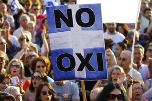 Menschen tragen ein blau-weißes Plakat mit den Aufschriften "No" und "Oxi"