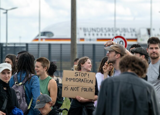 Teilnehmer einer Demonstration gegen das geplante Abschiebezentrum am Flughafen BER tragen unter anderem ein Plakat mit der Aufschrift Stop! Immigration is not Politic