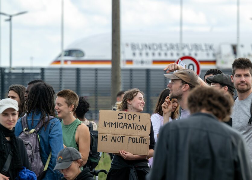 Teilnehmer einer Demonstration gegen das geplante Abschiebezentrum am Flughafen BER tragen unter anderem ein Plakat mit der Aufschrift Stop! Immigration is not Politic