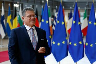 Ein Mann steht vor Flaggen der Euopäischen Union