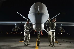 Eine amerikanische Reaper-Drohne wird von zwei Soldaten in der Nacht gewartet