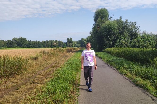 Ein Mann mit "Free Maja"-T-Shirt auf einem Weg im Grünen