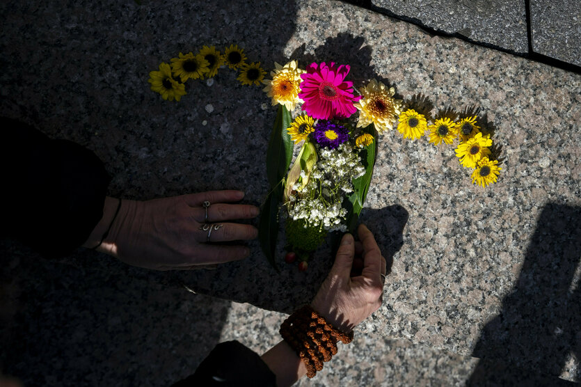 Hände legen Blumen in Form eines Uterus