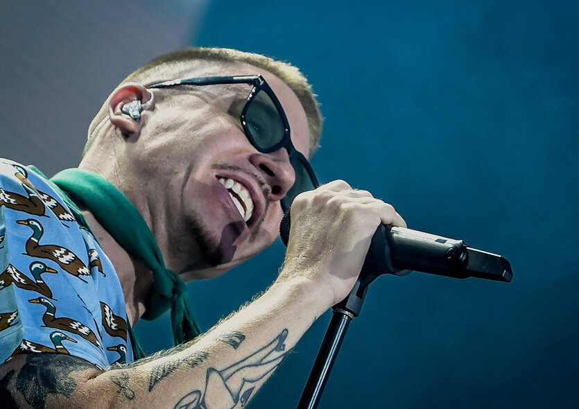Macklemore rappt auf einer Bühne in ein Mikrofon