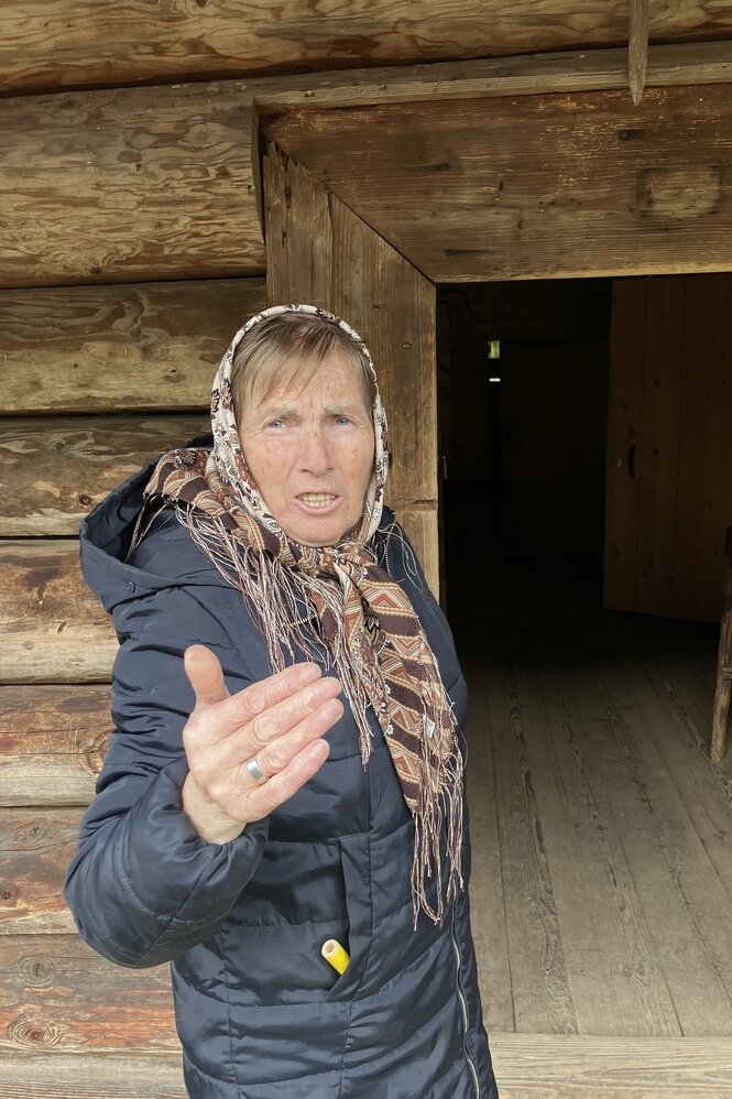 Weselka steht vor einem Holzhaus und spricht