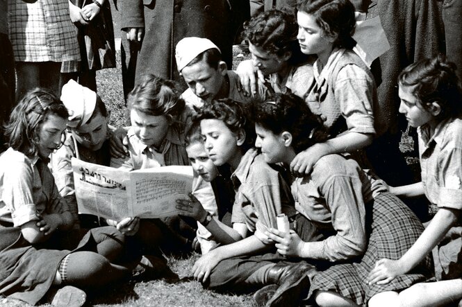 Eine historische Aufnahme zeigt junge Leute, die eine Zeitung lesen