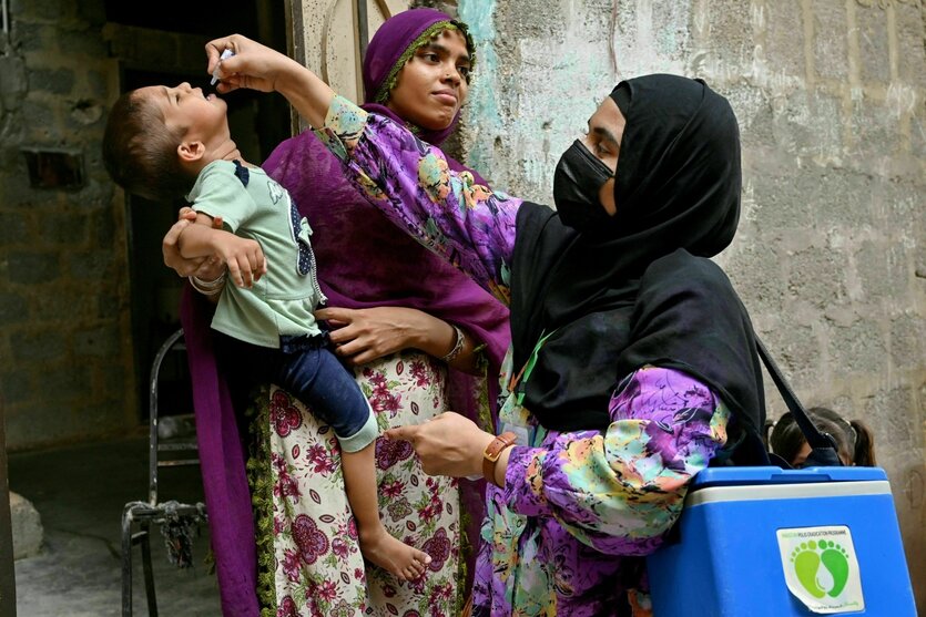 Verschleierte Frau gibt Kind eine Polio-Schluck-Impfung