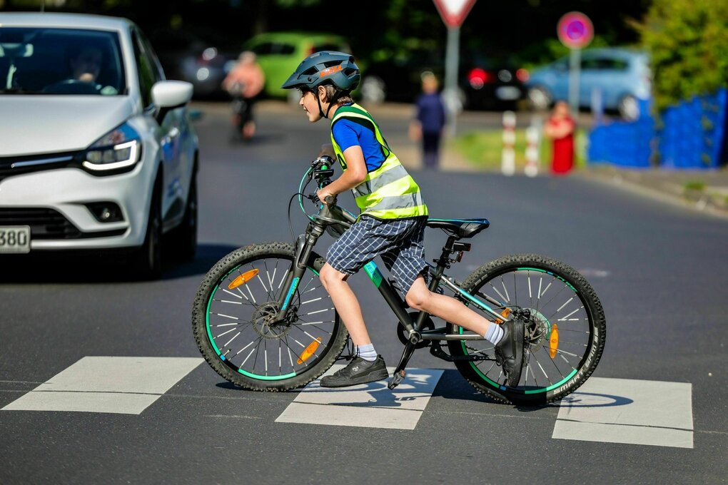Ein Grundschüler schiebt sein Fahrrad über einen Zebrastreifen an einer Grundschule