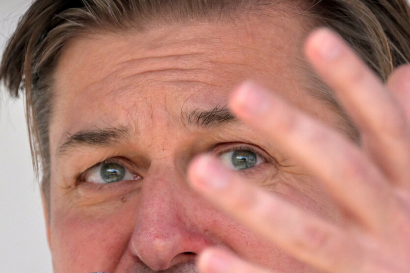 Die Augen eines Mannes (Maximilian Krah), der seine Stirn runzelt. Auch seine Hand ragt ins Foto