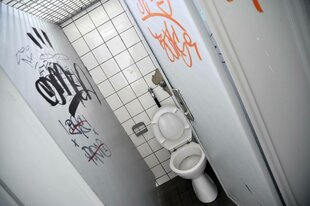 Eine offene Toilettenkabine mit Graffiti an den Wänden