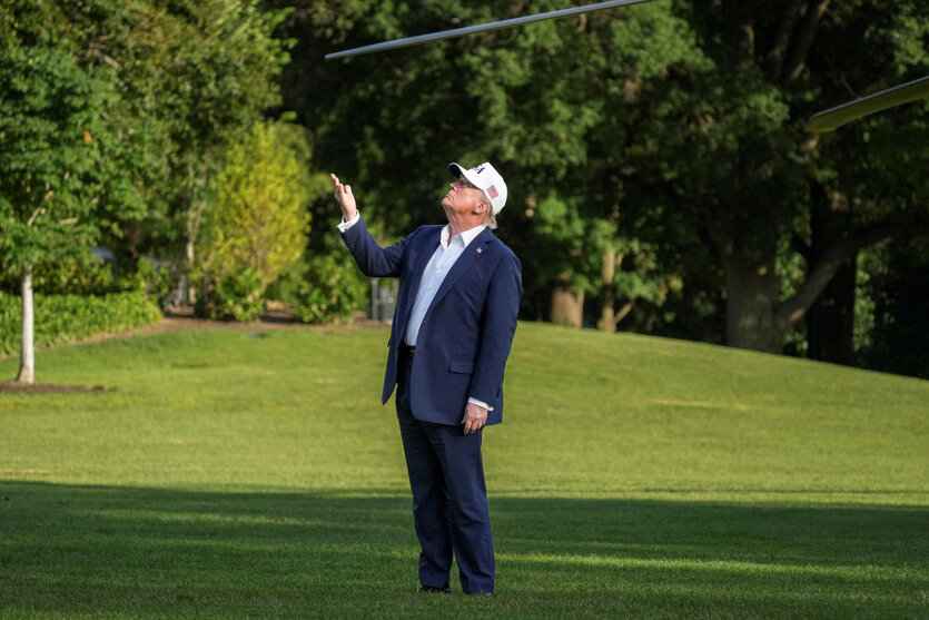 Donald Trump steht auf einer Wiese und guckt gen Himmel