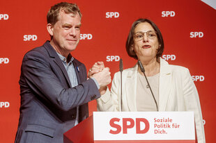 Ulf Kämpfer (SPD), Oberbürgermeister in Kiel, und Serpil Midyatli (SPD), Landes- und Fraktionsvorsitzende, versichern sich und ihrer Partei auf der Bühne des Landesparteitag ihre gegenseitige Solidarität für den Wahlkampf 2027.
