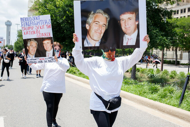 Zwei Menschen halten bei einer Demo Plakate in die Höhe, auf denen ein gemeinsames Foto von Donald Trump und Jeffrey Epstein zu sehen ist.