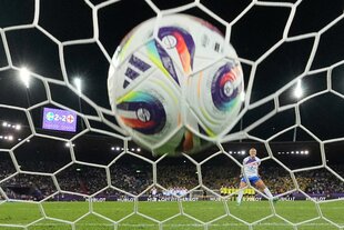 Ein Fußball wird ins Tornetz geschossen.