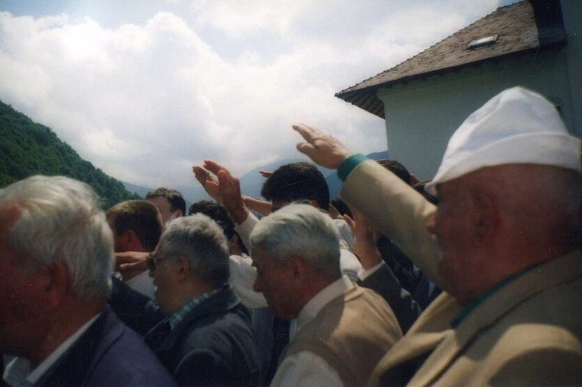 Männer stehen in einer Berglandschaft und heben ihre Arme zum faschistischem Gruß