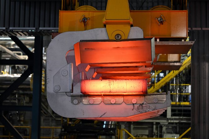 Eine glühende Bramme wird mit einem Kran aus der Stranggießanlage bei Thyssenkrupp Steel transportiert.