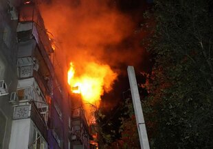 Ein Wohnhaus bei Nacht, aus dem Feuer lodert