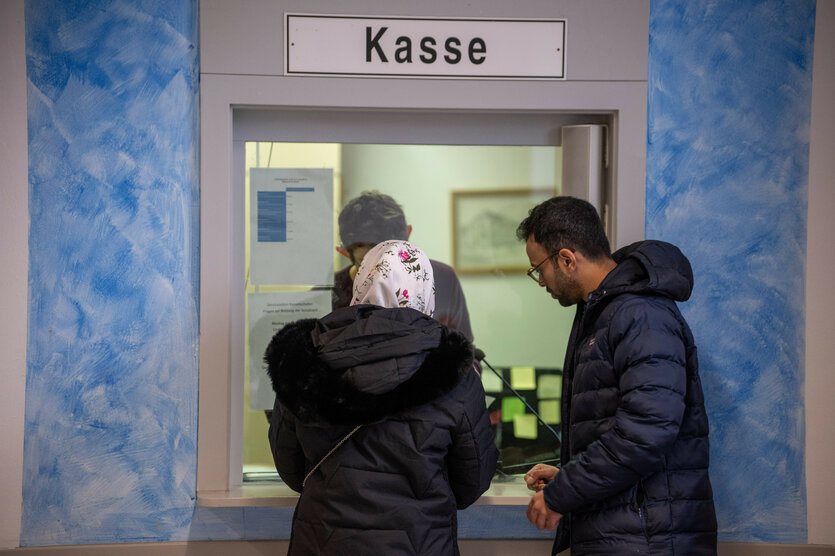 Eine Frau erhält im Beisein eines Dolmetschers an der Kasse der Aufnahmeeinrichtung für Asylbegehrende in Trier ihre Bezahlkarten für Geflüchtete in Rheinland-Pfalz. Die Bezahlkarte ist Teil eines Pilotprojekts.