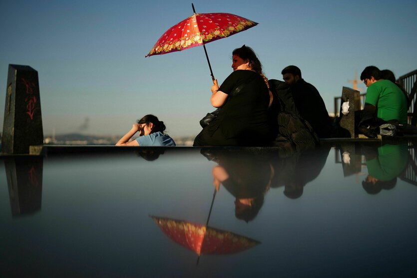 Sitzende Frauen in Istanbul, eine von ihnen schützt sich mit einem regenschirm gegen die Sonne