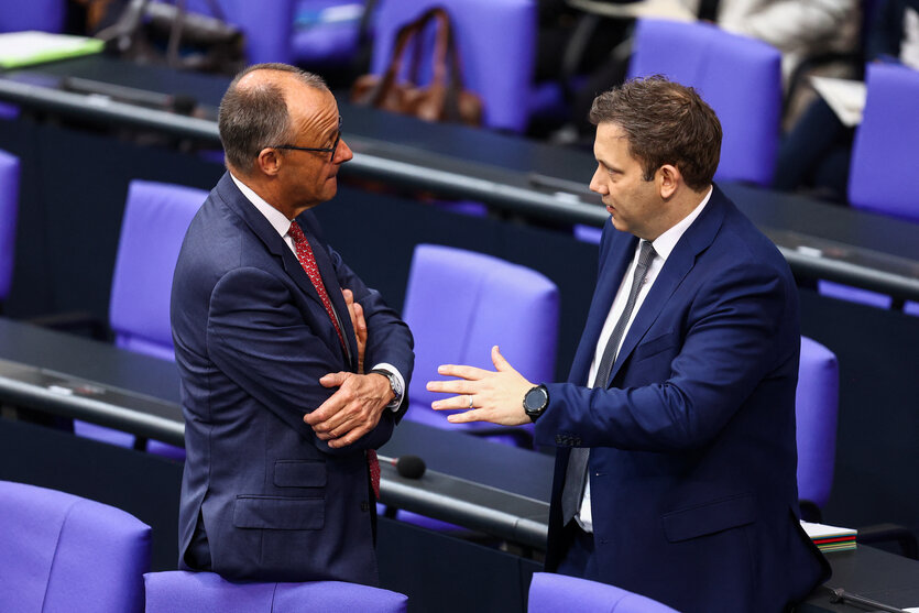 Zwei Männer in Anzügen vor den blauen Sitzen des Bundestages