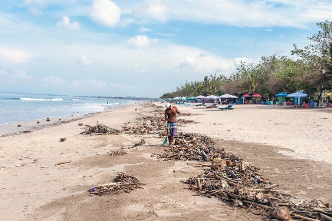 Ein Mann säubert einen vermüllten Strand