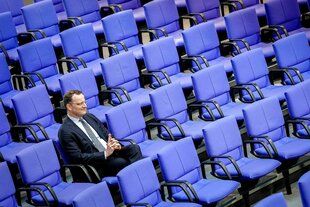Jens Spahn sitzt ganz allein in den leeren Sitzreihen des deutschen Bundestags
