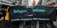 Das große Banner mit der Aufschrift "Refugees Welcome" getragen von Demonstranten