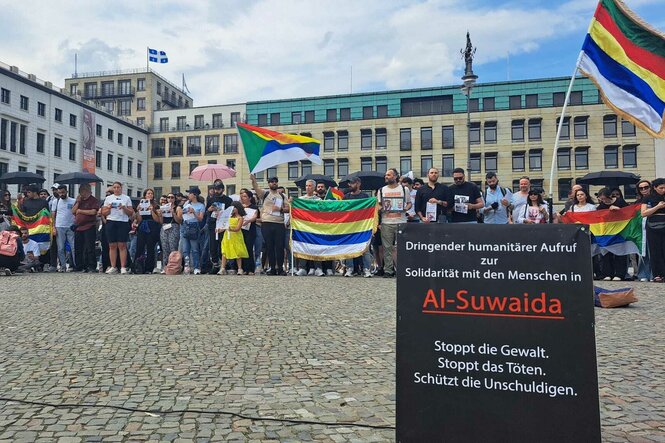 Eine Menschenmenge mit Plakaten Nahe des Brandenburger Tors ins Berlin