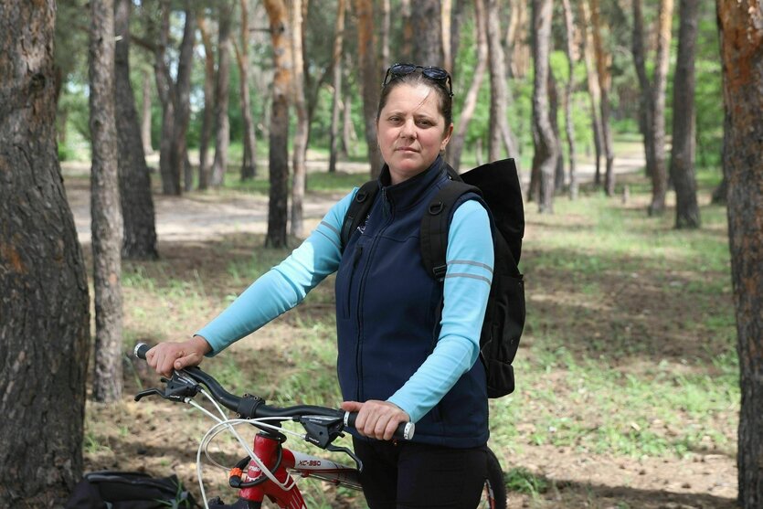 Eine Frau steht mit ihrem Fahrrad in einem Wald
