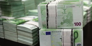 100-Euro-Scheine liegen in Stapeln auf einem Tisch