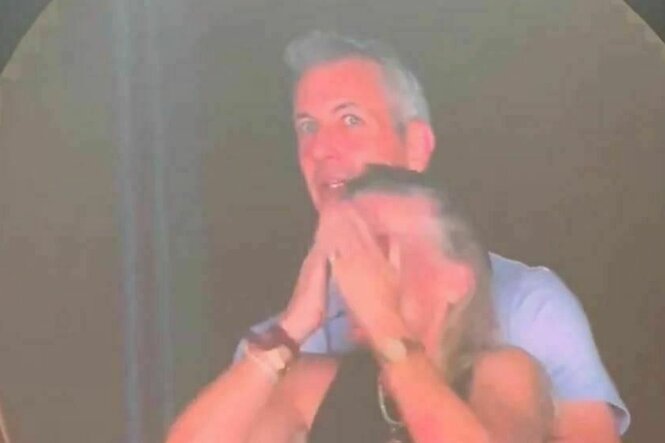 Ein Mann steht hinter einer Frau, die sich die Hände vor das Gesicht hält