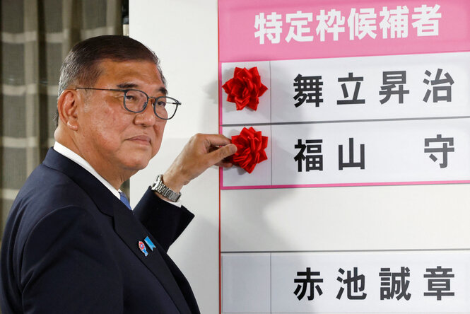 Ein Mann, Higeru Ishiba, steckt eine rote Rose an eine Anzeigentafel