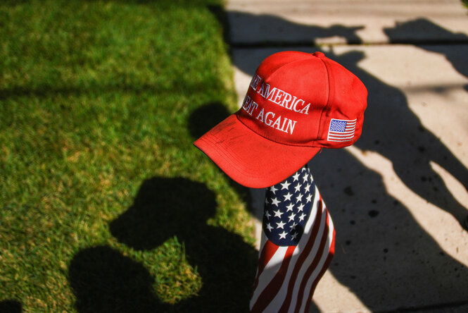 Eine Basecap mit der Aufschrift "Make America great again" steckt auf einer US-Flagge