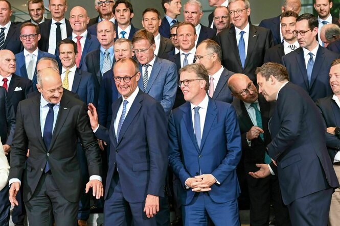 Viele Männer stehen parat für ein Gruppenbild mit Bundeskanzler Friedrich Merz