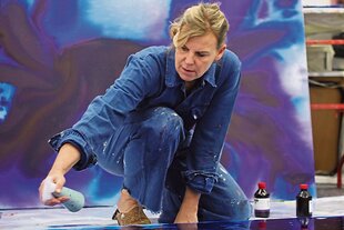 Petra Höcker kniet am Boden und bearbeitet ein Bild.