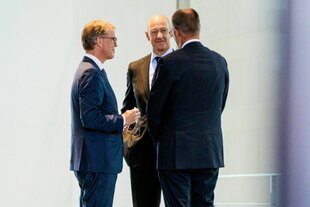 Drei Männer stehen beisammen und unterhalten sich
