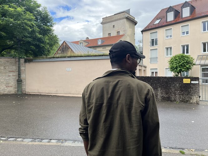 Ein Mann steht auf einer Straße, ist aber nur von hinten zu sehen