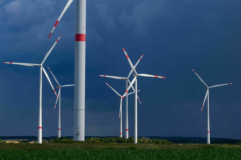 Dunkle Gewitterwolken ziehen über einen Windenergiepark.